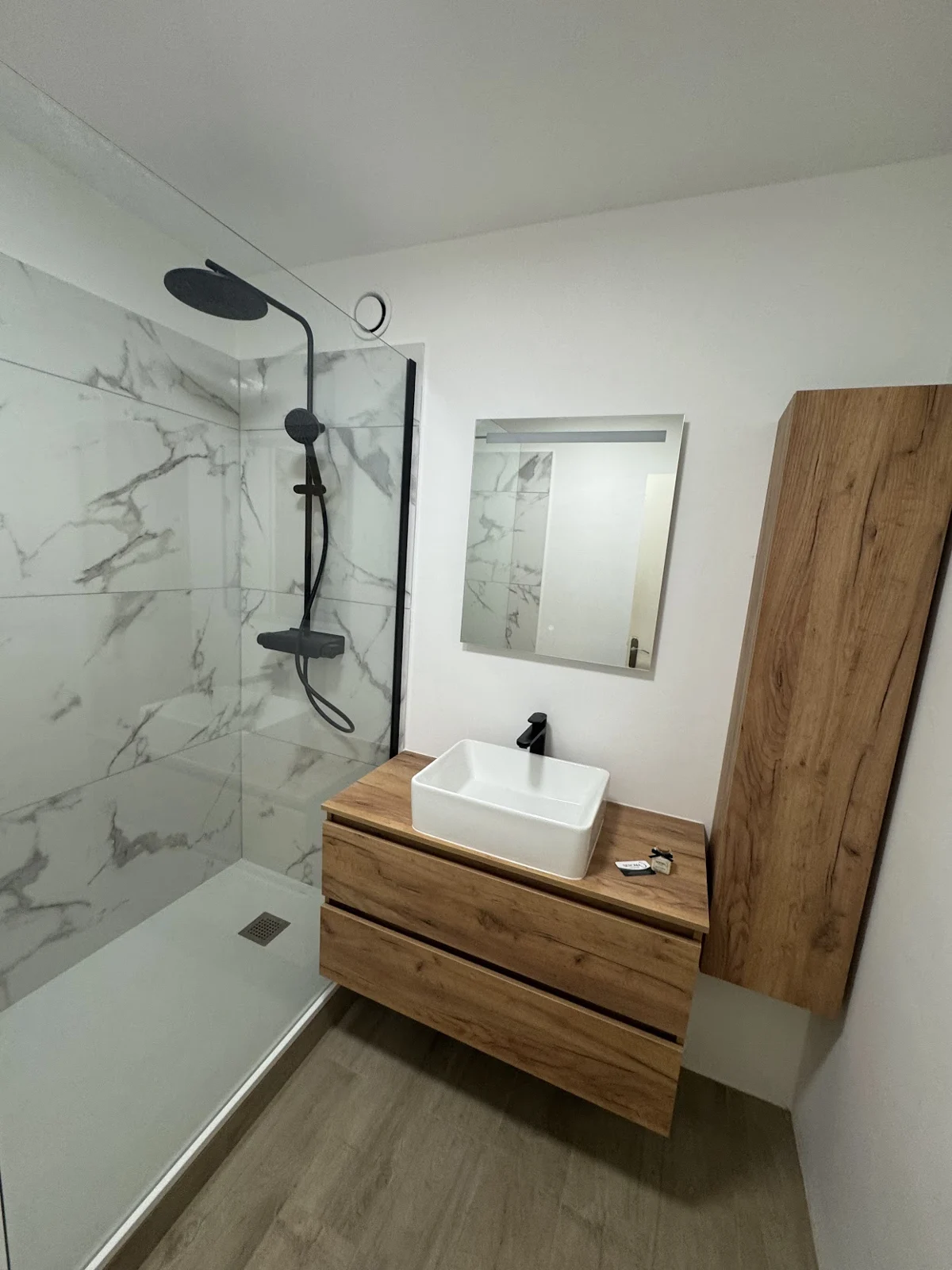Salle de bain avec meuble bois, douche et robinetterie noire