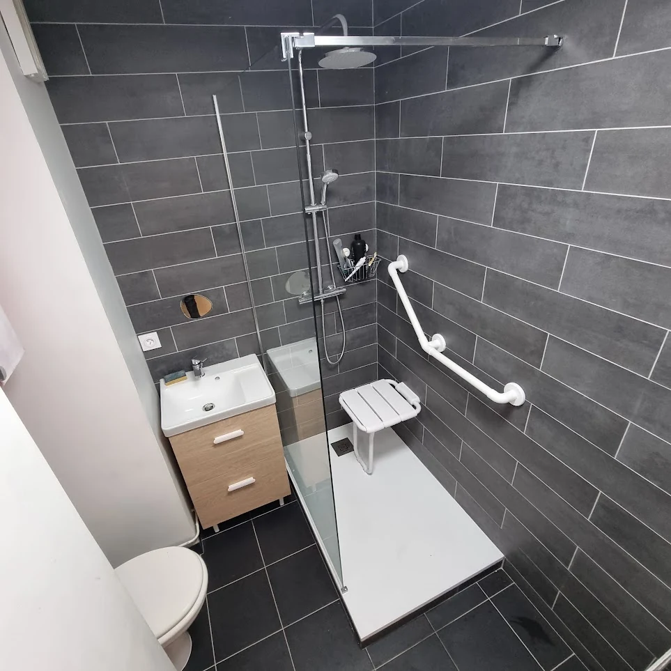 Salle de bain avec douche équipée d’un siège et de barres d’appui