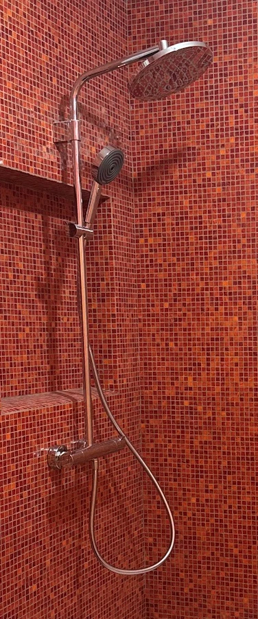 Colonne de douche chromée sur mosaïque rouge